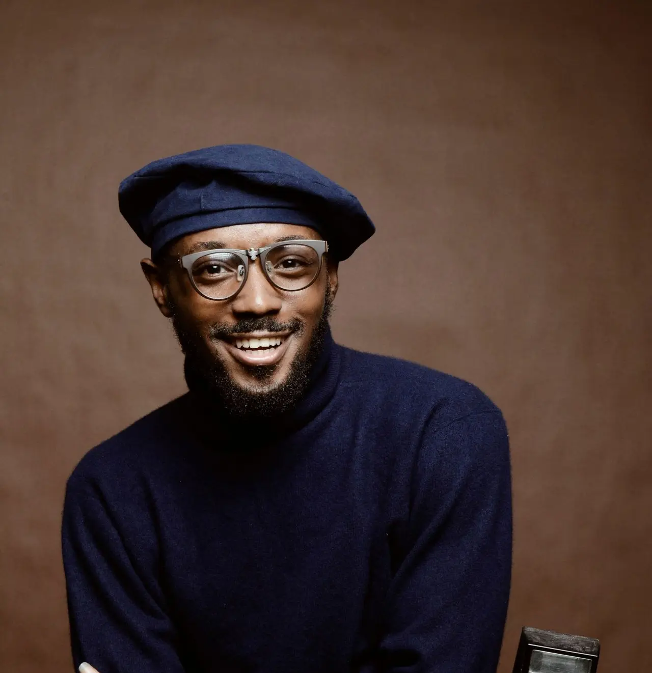 smiling man wearing black turtleneck shirt holding camrea