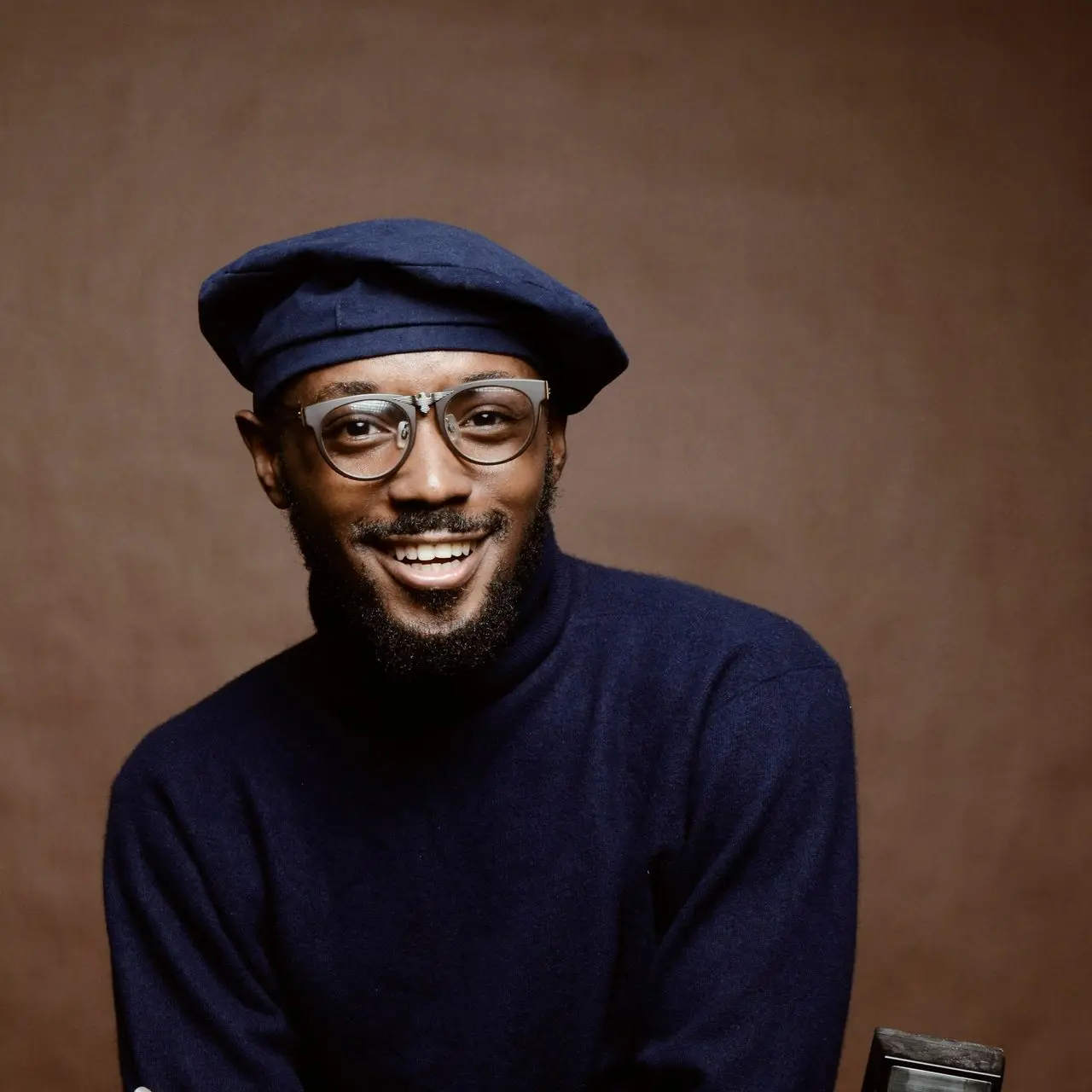 smiling man wearing black turtleneck shirt holding camrea